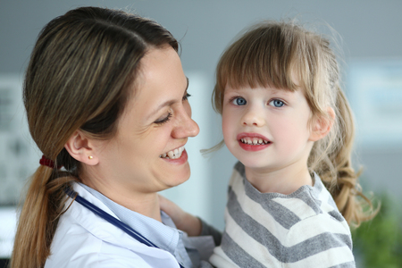 Paediatric doctor holding and hugging little cute girl patientの写真素材
