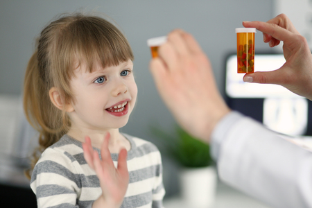 Cute little patient girl having fun selecting a bottle of medicationsの写真素材