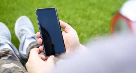 Male hand hold a smartphone against green backgroundの写真素材