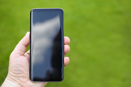 Male hand hold a smartphone against green backgroundの写真素材