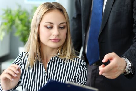 Beautiful blonde female clerk talking with male colleagueの写真素材