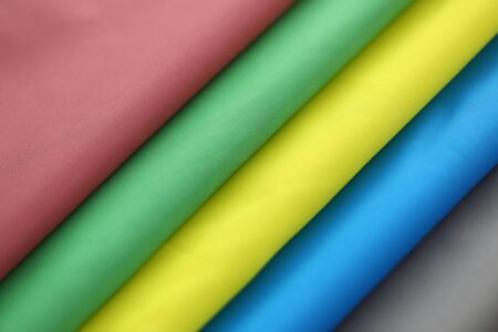 Colorful textile clothing of various kinds of special vibrant materials stacked in big pile of different colors red, green, yellow, blue, and grey. Fashioner market conceptの写真素材