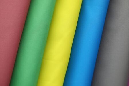 Various kinds of special vibrant materials stacked in big pile of different colors red, green, yellow, blue, and grey. Clothes made of tender velvet and silk. Fashioner market conceptの写真素材
