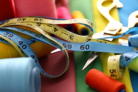 Focus on colorful fabric strips with printed numerals used to produce clothes with right proportions and length. Utility lying on table covered in textile. Fashioner market concept. Blurred backgroundの写真素材