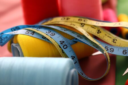 Focus on device lying on table covered in textile. Colorful fabric stripes with printed numerals used to produce clothes with right proportions and length. Fashioner market concept. Blurred backgroundの写真素材