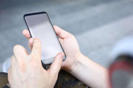 Focus on male hands holding smartphone. Man surfing internet or typing something on cellphone. Latest technology concept. Copy space on screen. Blurred backgroundの写真素材