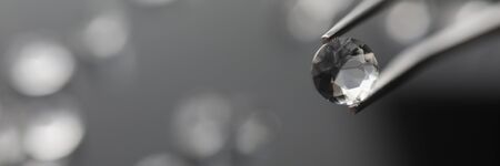 The jeweler holds a diamond in tweezersの写真素材