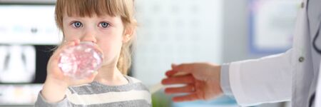 Cute little girl getting water in doctor officeの写真素材