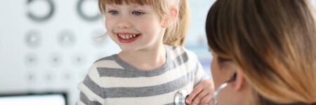 Female doctor working with cute smiling little girl at her officeの写真素材