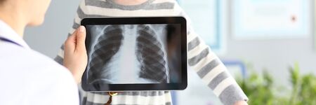 Female doctor examining little girl with ultra modern scanning tablet pc deviceの写真素材
