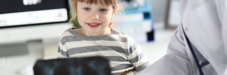 Female paediatrician working with cute little girl at her office explaining diagnosisの写真素材