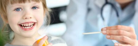 Cute smiling happy little girl hold in hand bottle of tablets at doctor officeの写真素材