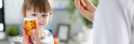 Cute little patient girl having fun selecting a bottle of medicationsの写真素材