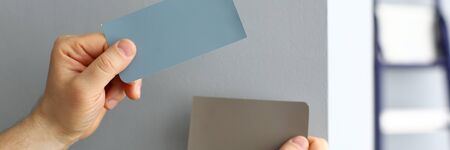 Man holding in arms colour palettes while choosing new paint for house