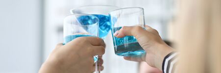 Focus on festive glasses of delicious blue alcohol. People celebrating successful signing profitable contract. Friendly teamwork concept. Blurred backgroundの写真素材