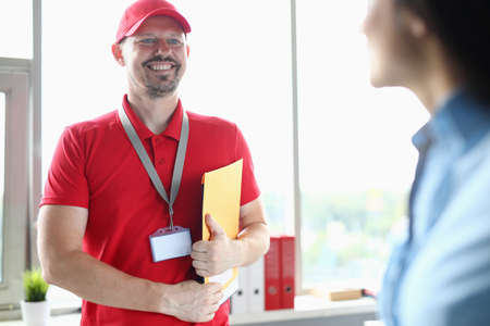 Male courier in office smiles and holds documents in his hands.の写真素材
