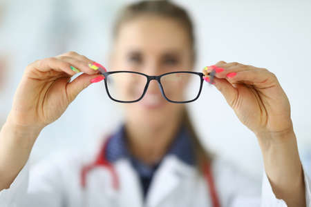 Woman doctor holding glasses in her hands closeupの写真素材