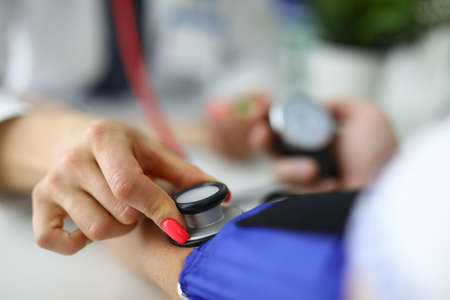 Female doctor measures pressure of a patient with medical office.の写真素材