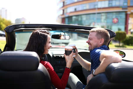 Woman and man are drinking a hot drink in car and laughing.の写真素材