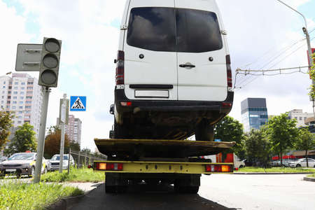 Minibus stands on a tow truck at traffic light closeupの写真素材
