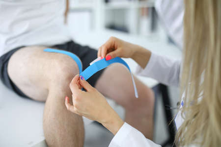 Nurse glue kinesio tape on patients kneeの写真素材