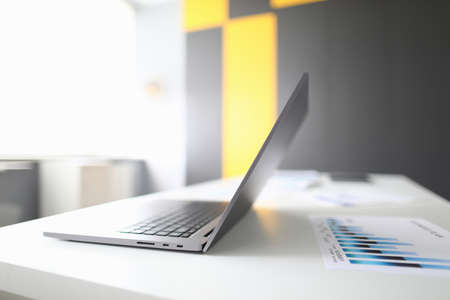 In office there is laptop on table and charts with commercial indicatorsの写真素材