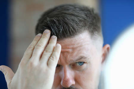 Man applying hair gel to his hair closeupの写真素材