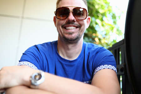 Man in sunglasses sits and smiles closeupの写真素材