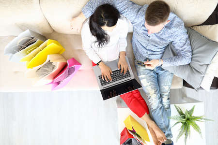 Woman and man are sitting on couch with credit card and are shopping online.の写真素材