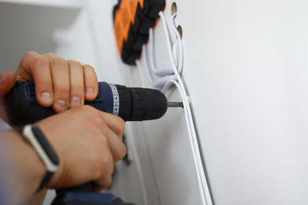 Man holds hammer drill in his hands and drills hole.