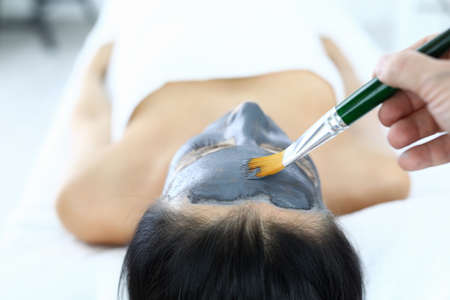 Cosmetic clay mask is applied to woman in beauty salon.の写真素材