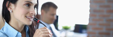 Young woman is talking on microphone in an office.の写真素材
