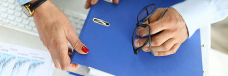 Man and woman in office hold hands on folder with documentsの写真素材