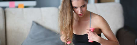 Woman holds dumbbells in her hands and does exercises