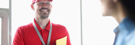 Male courier in office smiles and holds documents in his hands.