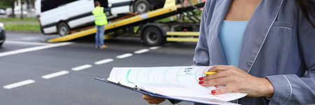 Female agent fills out insurance at the scene of accident.の写真素材