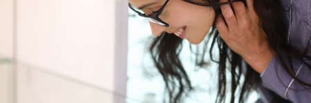 Woman chooses product leaning over glass display case.