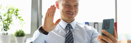 Businessman in the office talking on video call on smartphone.