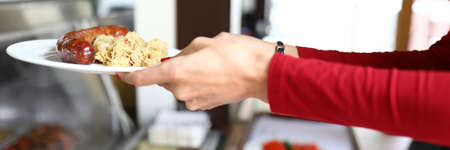 Woman is holding plate of food in bistro.の写真素材