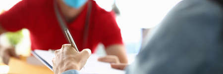 Client signs clipboard to courier wearing medical mask.の写真素材