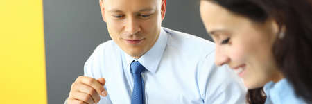 Businessman and businesswoman are sitting in office at table and looking at smartphoneの写真素材