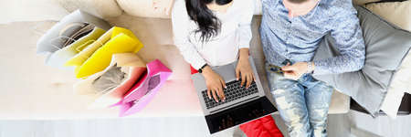 Woman and man are sitting on couch with credit card and are shopping online.の写真素材
