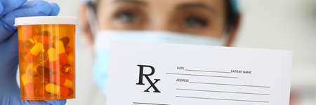 Pharmacist holds medicine and prescription in hand.の写真素材