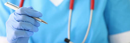 Gloved doctor holds clipboard and writes in it.の写真素材