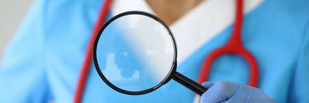 Medical researcher holds magnifying glass in his hands.の写真素材
