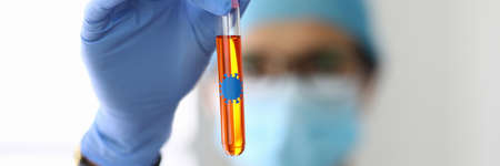 Laboratory assistant in protective mask holds flask with liquid containing bacteria.の写真素材