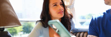 Woman looks at man with sad look and they are holding smartphones in their hands.の写真素材
