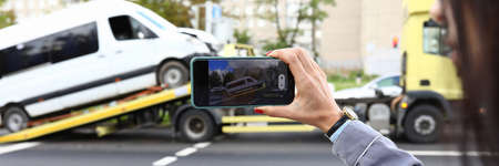 An insurance agent takes photo of crashed car after an accident on smartphone.の写真素材