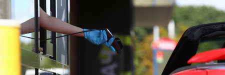 Gloved hand holds pos terminal and holds it out towards the carの写真素材