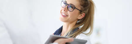 Woman in white coat smiles and communicates with an employee holding tablet in his hands.の写真素材